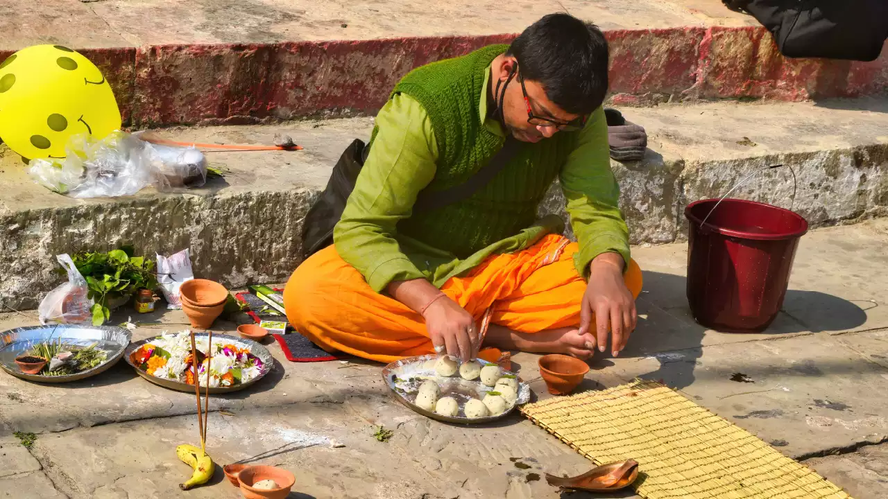 Pandit preparing offerings for an Online Pind Daan ceremony at a sacred river ghat