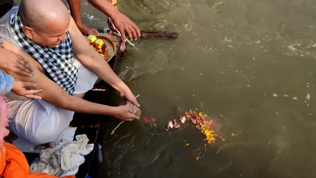 Family performing Asthi Visarjan with a pandit at a sacred river in India