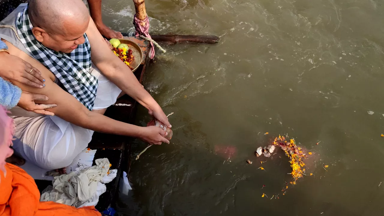 नौका से पवित्र संगम में पुष्प अर्पित करता एक परिवार — एनआरआई श्राद्ध पूजा प्रयागराज