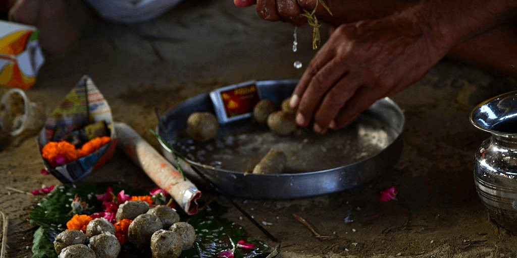Hands offering Pind Daan with water over sacred offerings